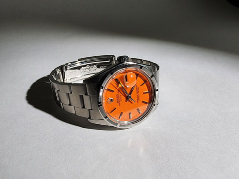Custom Vintage Rolex Date with a custom Tangerine dial and an original stainless steel band.